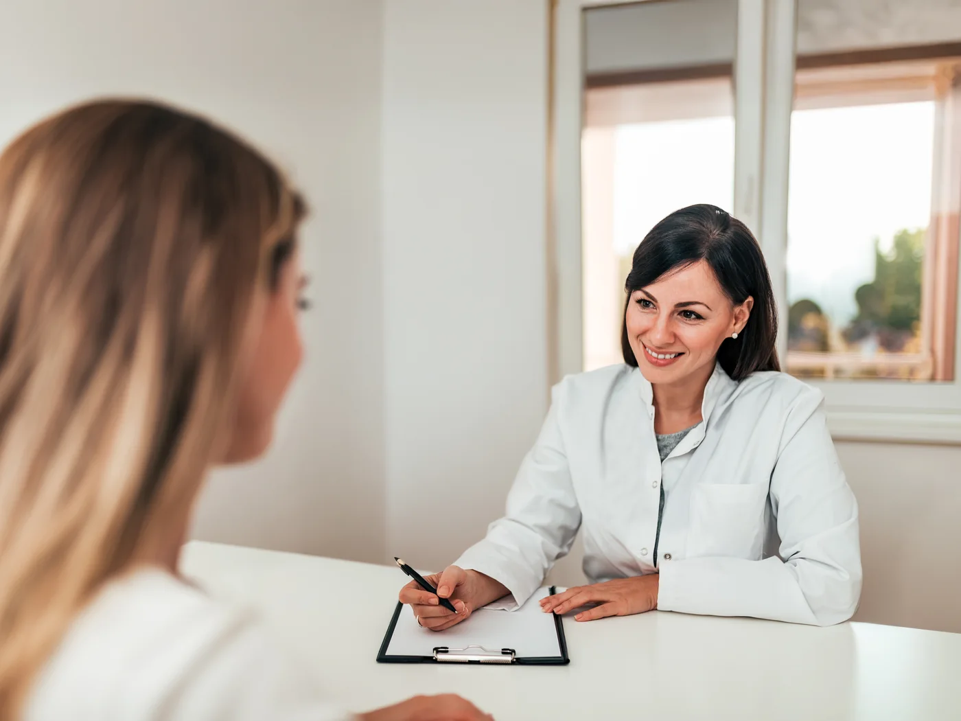 Médica conversa com paciente durante atendimento.